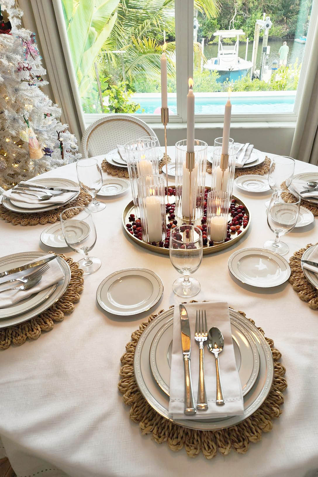 Dining table set with round woven placemats, white plates and cloth napkins